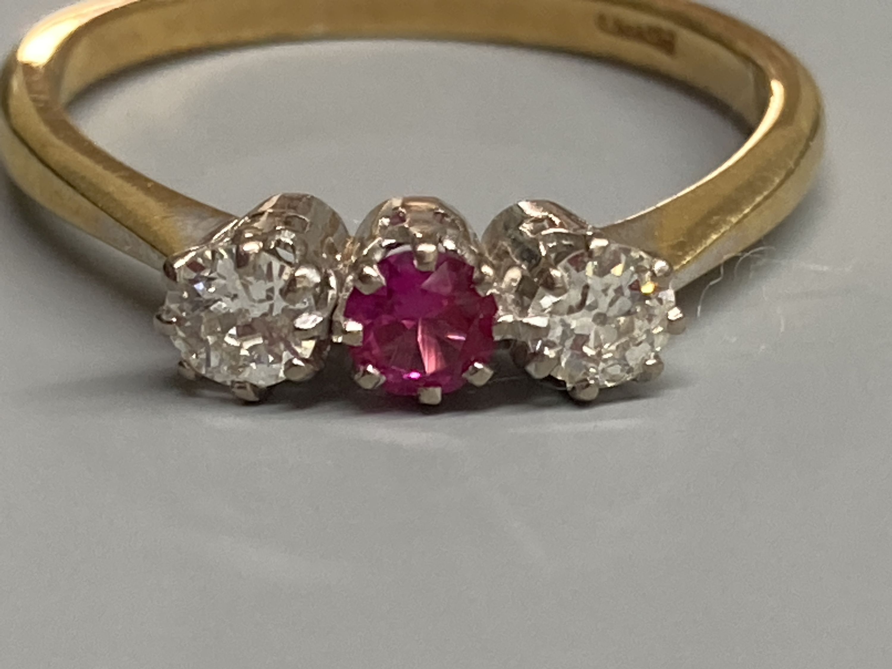 An 18ct, synthetic? ruby and diamond set three stone ring, size S, gross 3.6 grams.